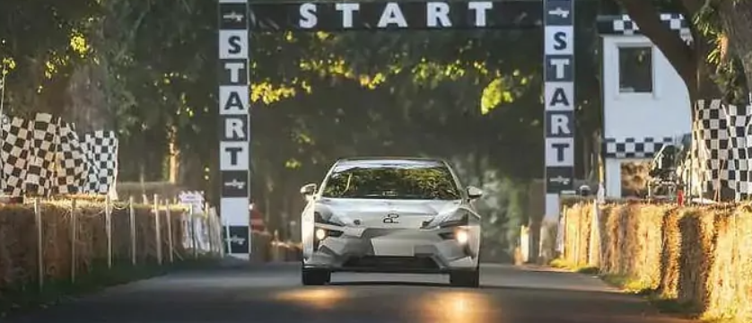 A car is driving through a start line on a road.