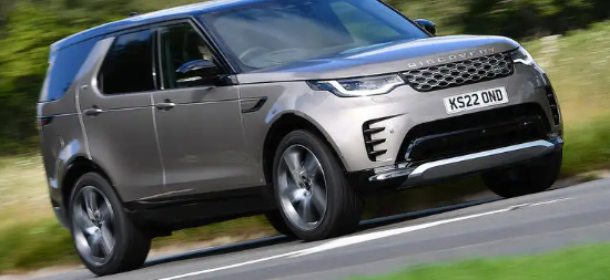 A gray land rover discovery is driving down a country road.