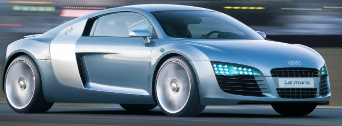 A silver audi r8 is driving down a road