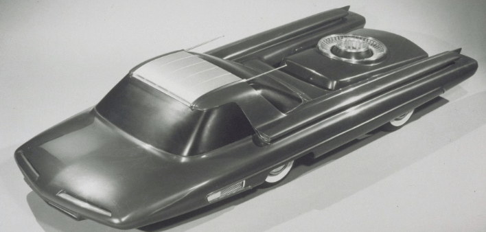 A black and white photo of a toy car on a table.