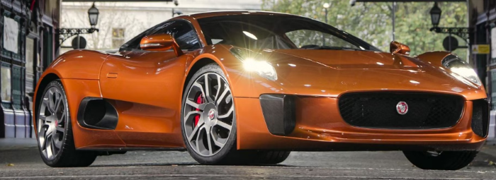 An orange sports car is parked in front of a building.