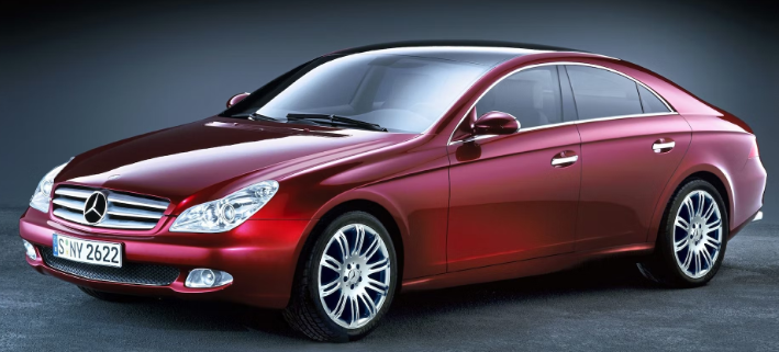 A red mercedes benz is parked on a gray surface