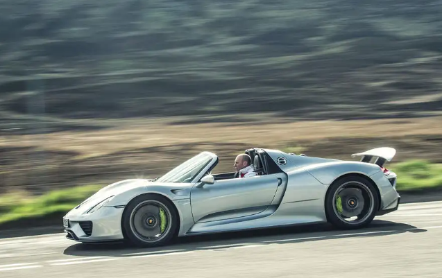 A silver sports car is driving down a road.