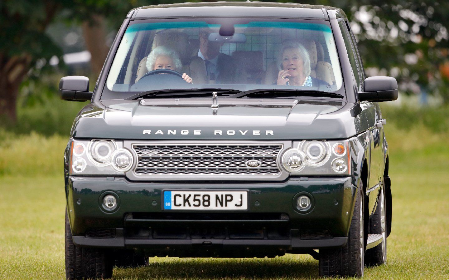 A black range rover is driving through a grassy field.