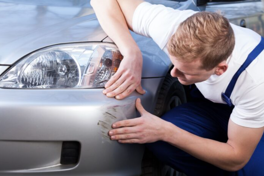 A man is scratching the front of a car
