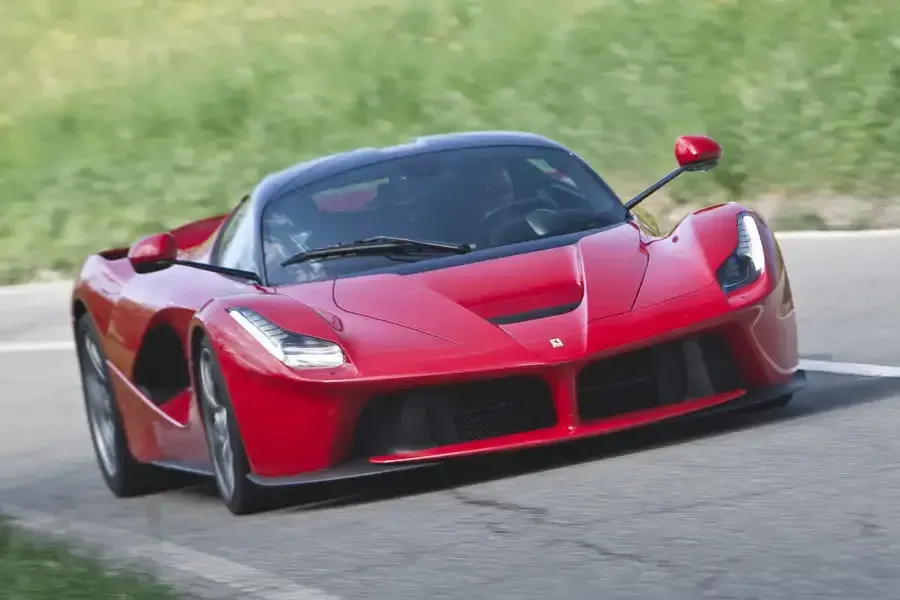A red ferrari laferrari is driving down a road.