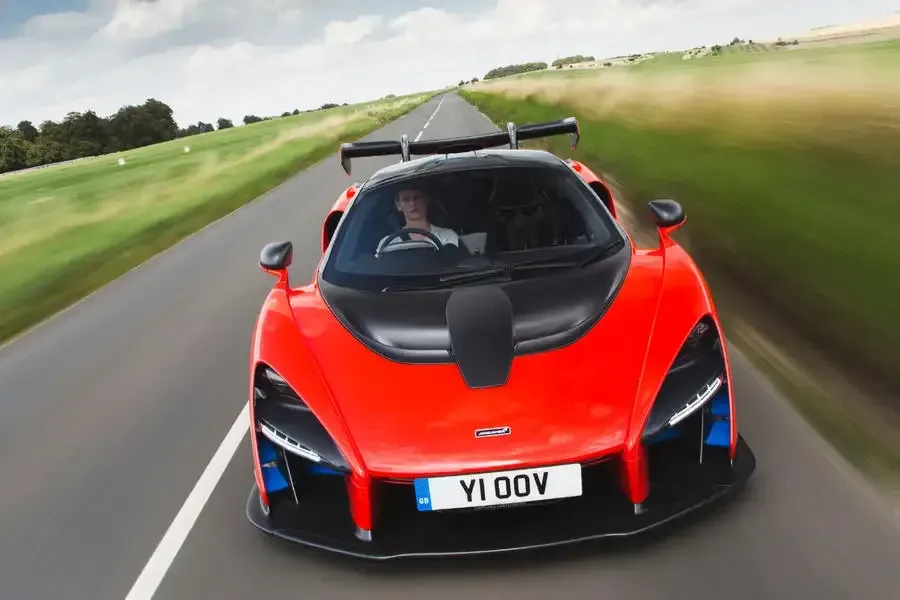 A red sports car is driving down a country road.