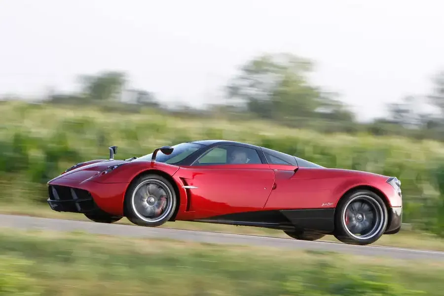 A red sports car is driving down a road.