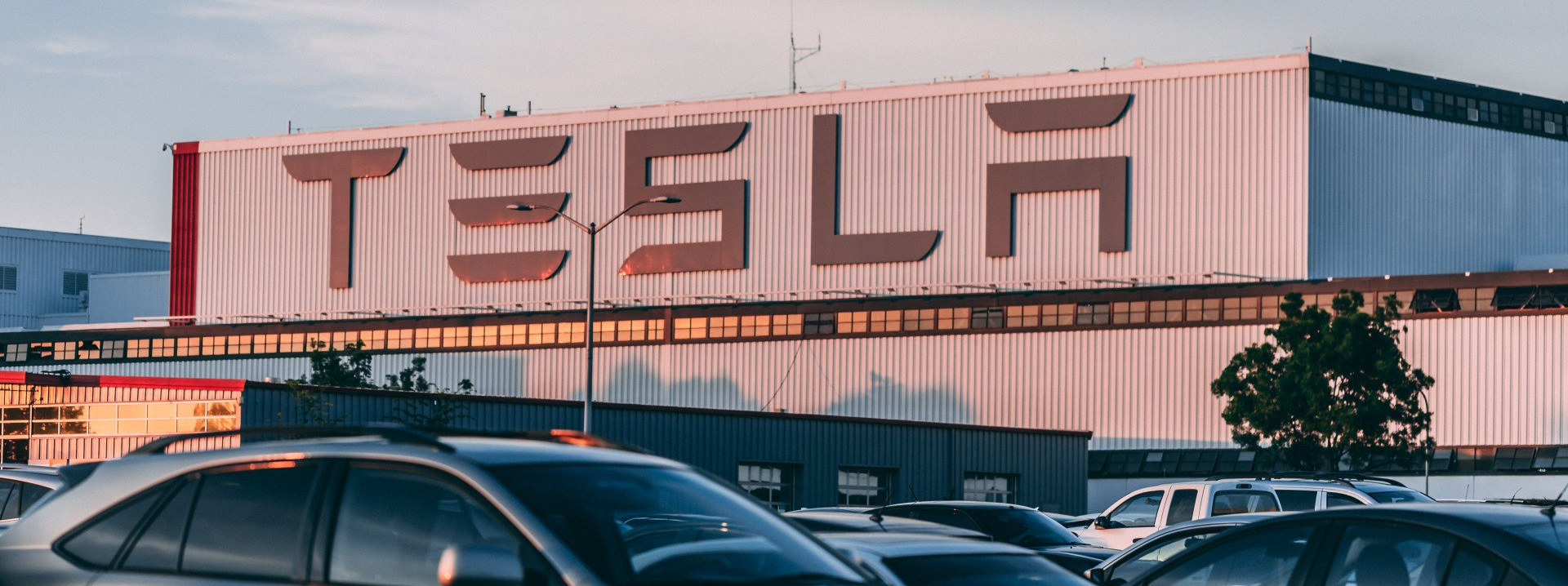 A tesla factory with cars parked in front of it.