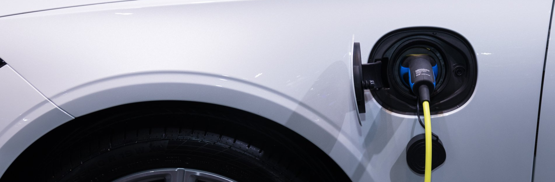 A close up of a white electric car being charged.