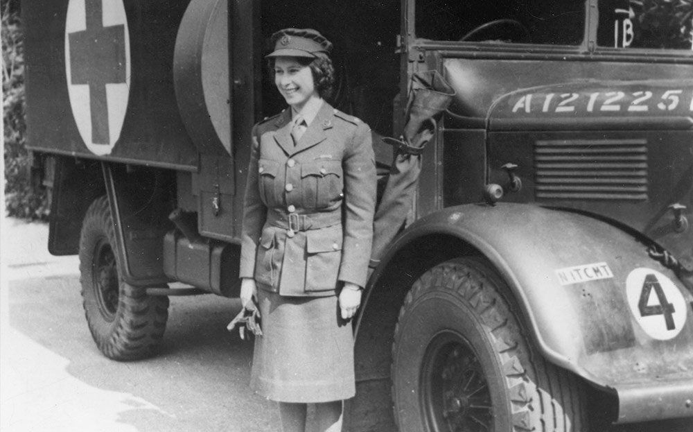 A black and white photo of a woman standing next to an ambulance