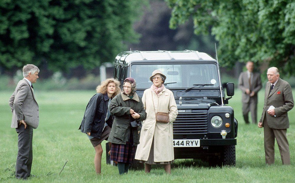 A group of people are standing in front of a land rover defender.