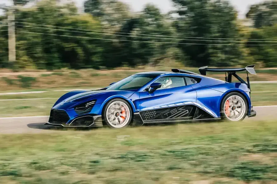 A blue sports car is driving down a road.