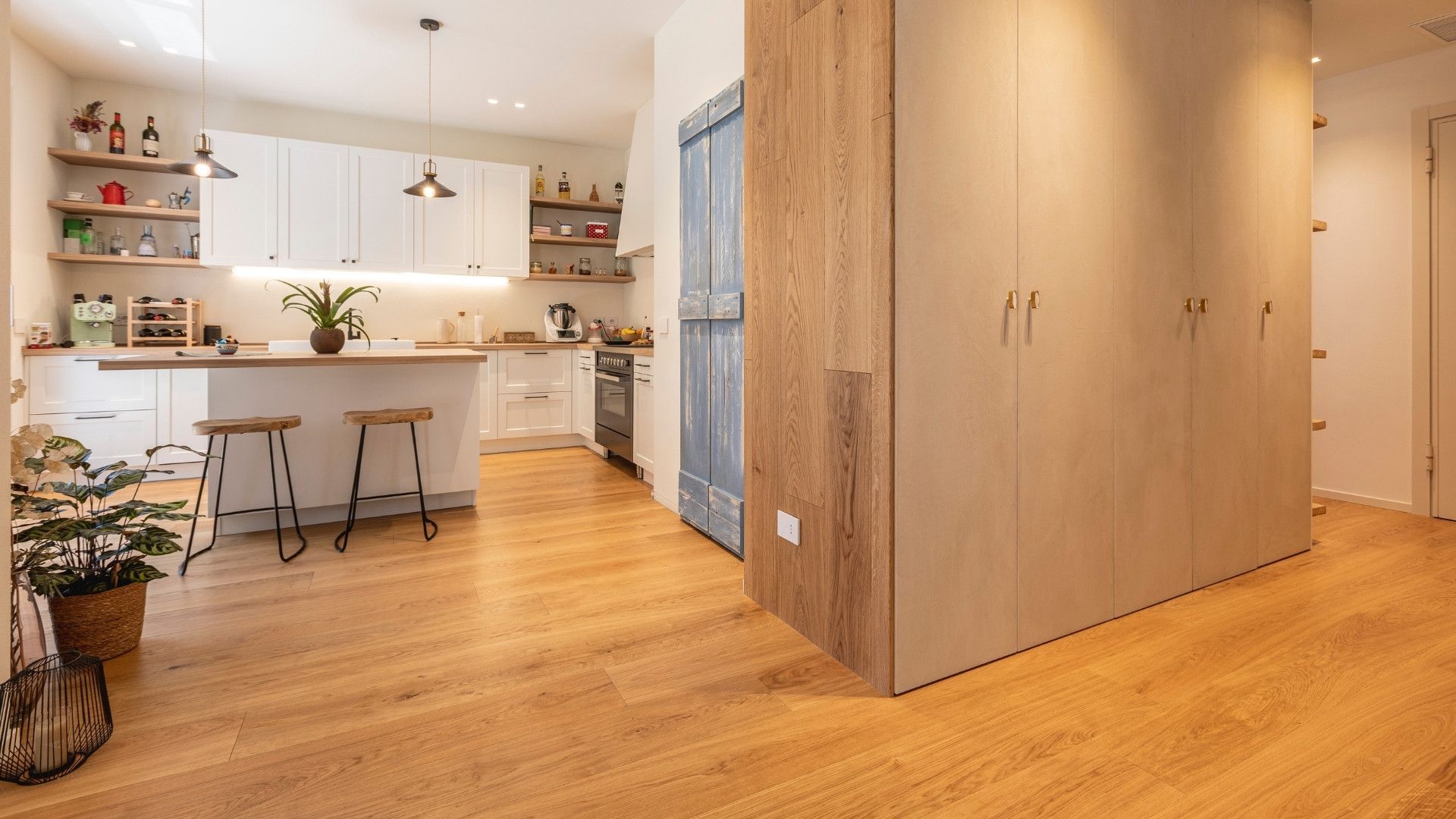 Una cucina con pavimenti in legno e armadi bianchi e una porta scorrevole.