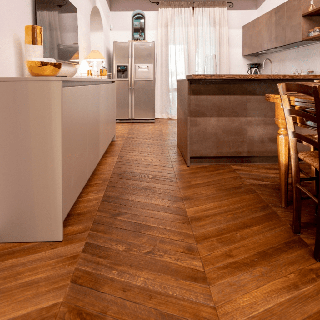 Una cucina con pavimento in legno e frigorifero in acciaio inox.