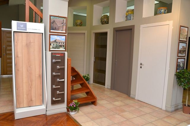 Una stanza con scala, esposizione di pavimenti e porte in legno.