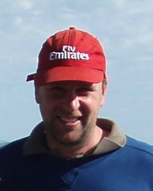 A man wearing a red hat that says fly emirates