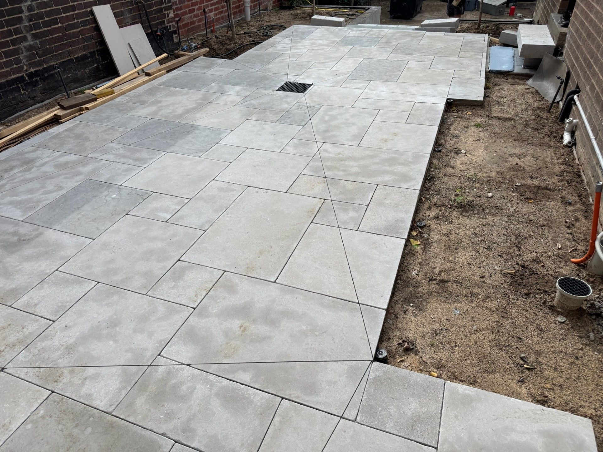 Freshly laid gray concrete pavers forming a patio or walkway beside a dirt yard