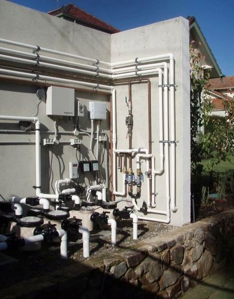 A wall with copper pipes and valves on it