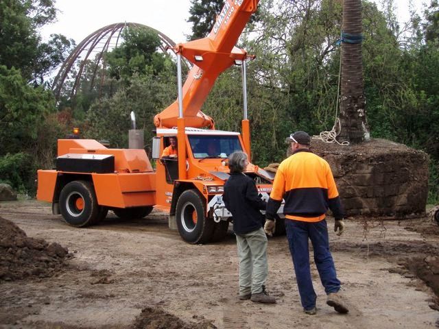 Two men are standing in front of an orange crane