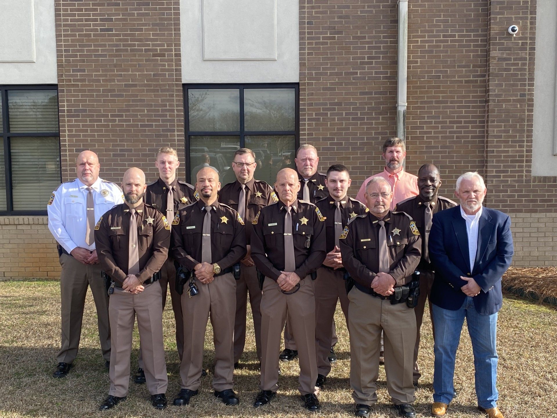 Group of uniformed law enforcement officers standing outside a brick building.