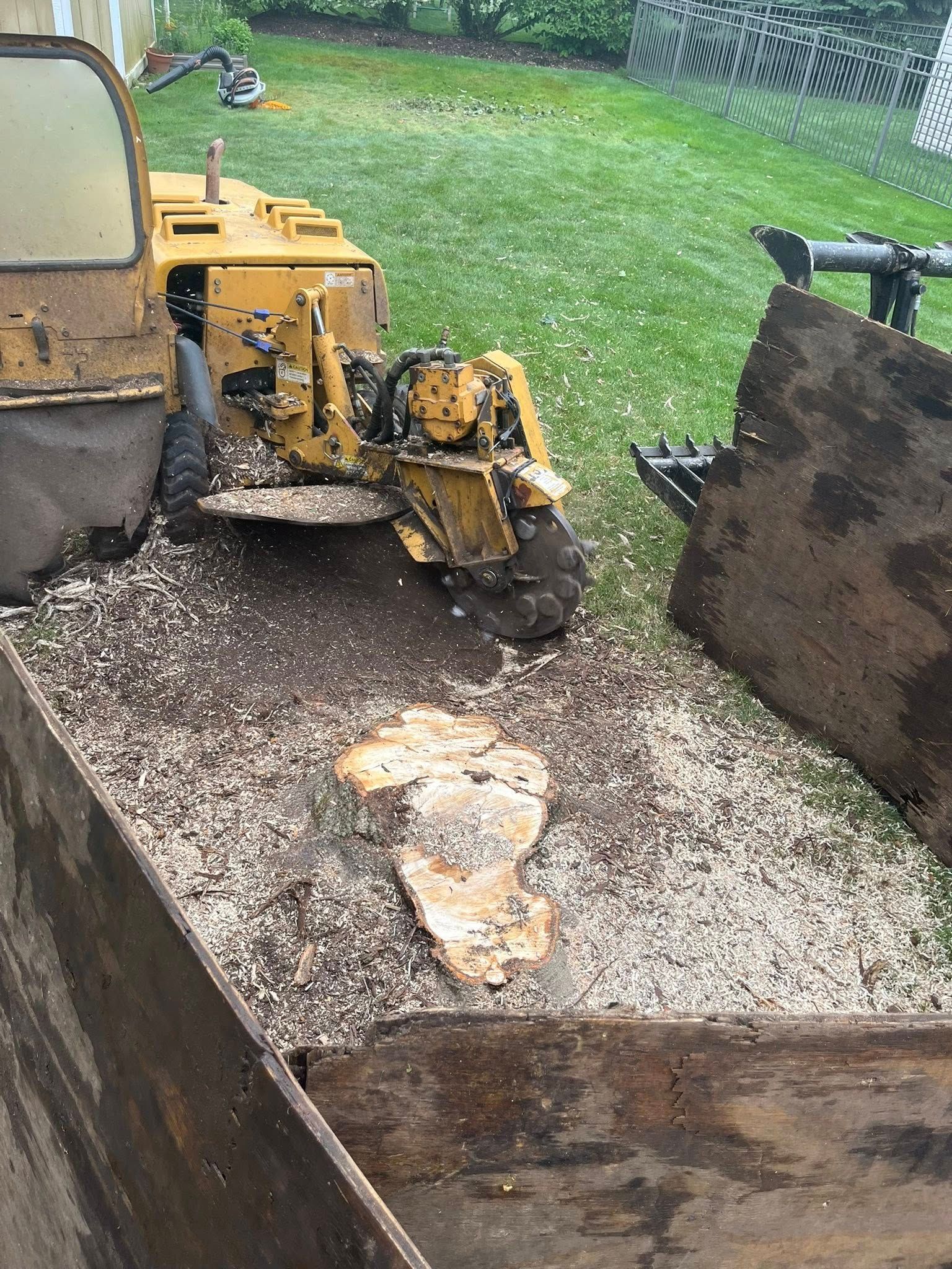 Small yellow excavator and loader bucket in gravel-filled trailer with large rocks