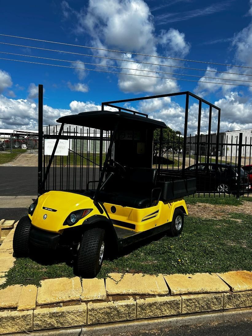 A Yellow Golf Cart Is Parked on The Side of The Road Next to A Fence — DTM Tamworth in Tamworth, NSW