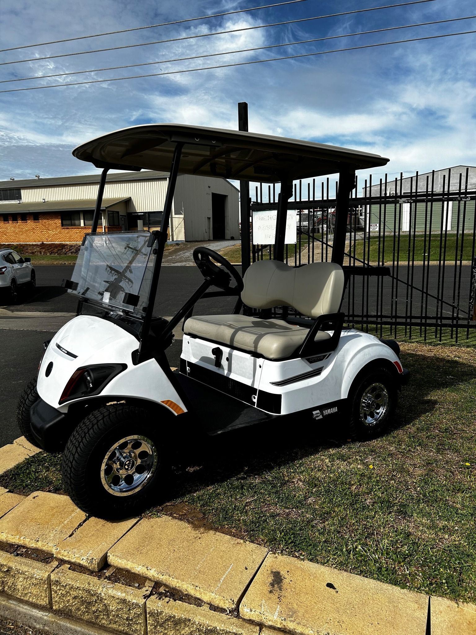 A White Golf Cart Is Parked on The Grass in A Parking Lot — DTM Tamworth in Tamworth, NSW