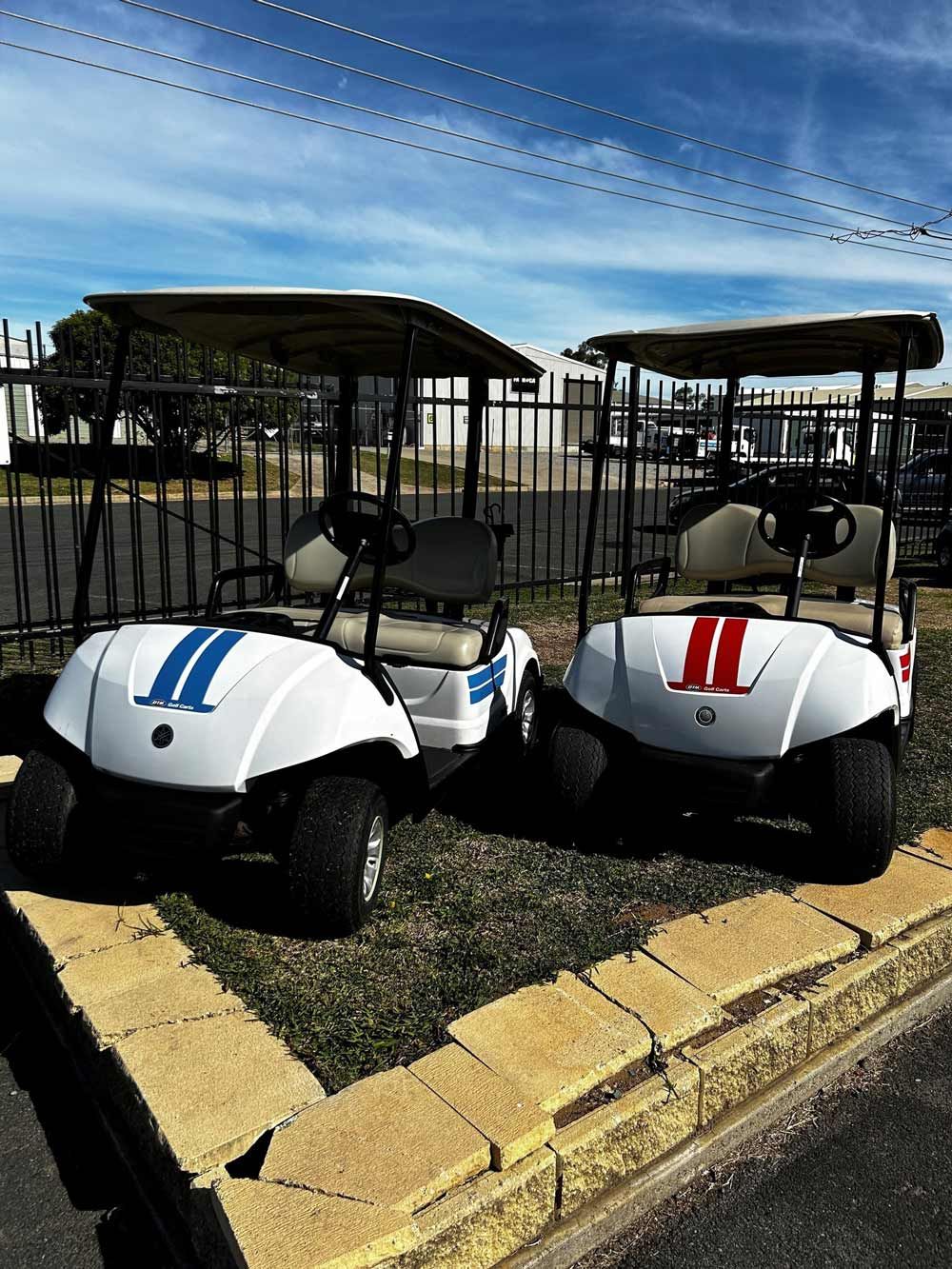 Two white golf carts with racing stripes parked side by side in Tamworth
