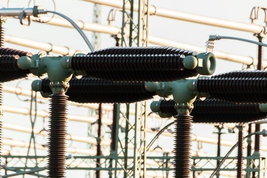 Equipo de subestación eléctrica con aisladores negros y líneas eléctricas metálicas.