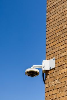 Cámara de seguridad montada en una pared de ladrillos contra un cielo azul