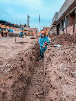 Un trabajador con equipo de seguridad azul se encuentra en una zanja profunda