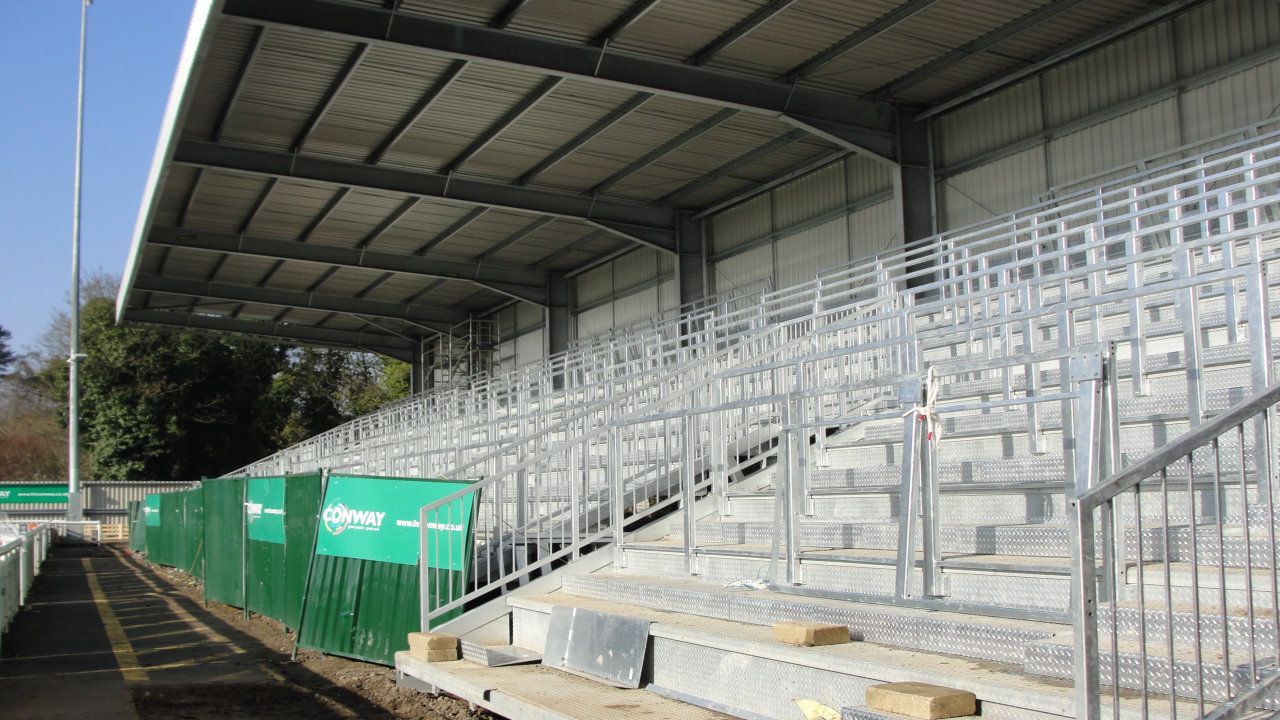 A stadium with rows of bleachers and a green fence.