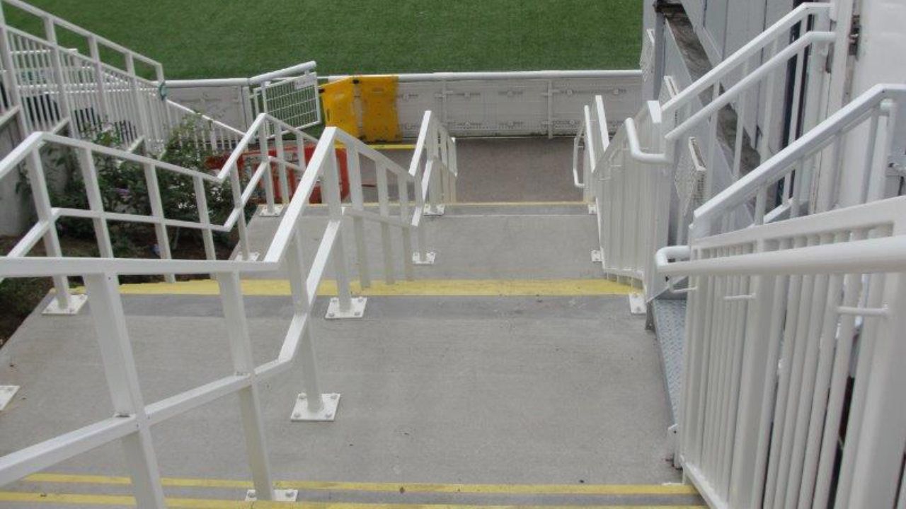 A set of stairs with a white railing and yellow lines