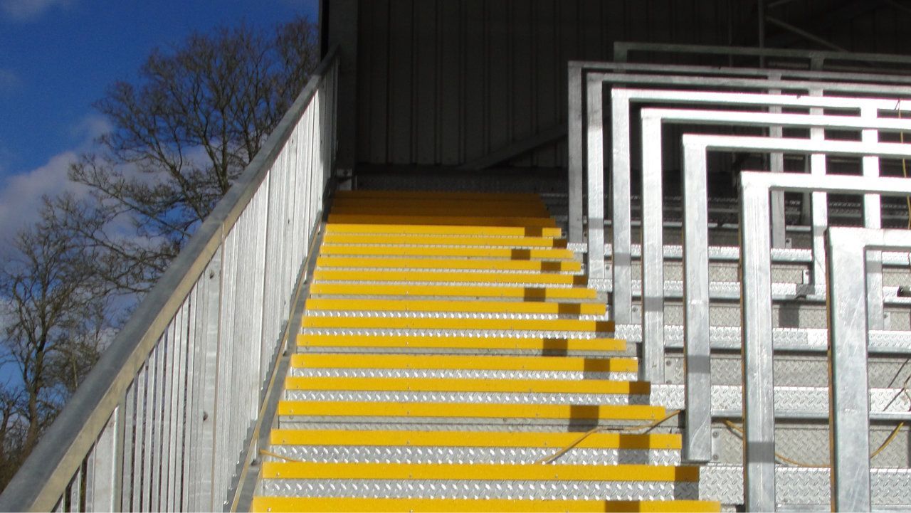 A set of stairs with yellow steps and a metal railing.