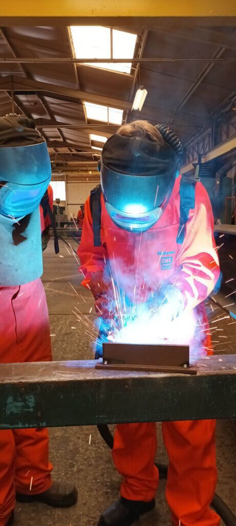 A man is welding a piece of metal in a factory.