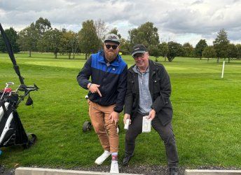 Two men are posing for a picture on a golf course.