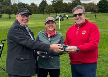 A man is giving a gift to a woman on a golf course.