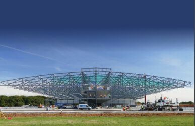 A large metal Reidsteel structure is being built in a field.