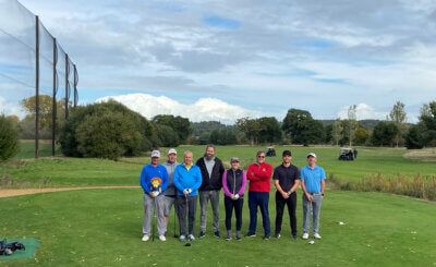A group of people are standing on top of a golf course.