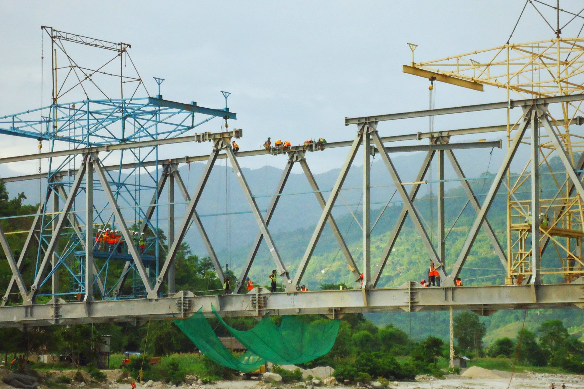 A bridge is being built over a river with mountains in the background
