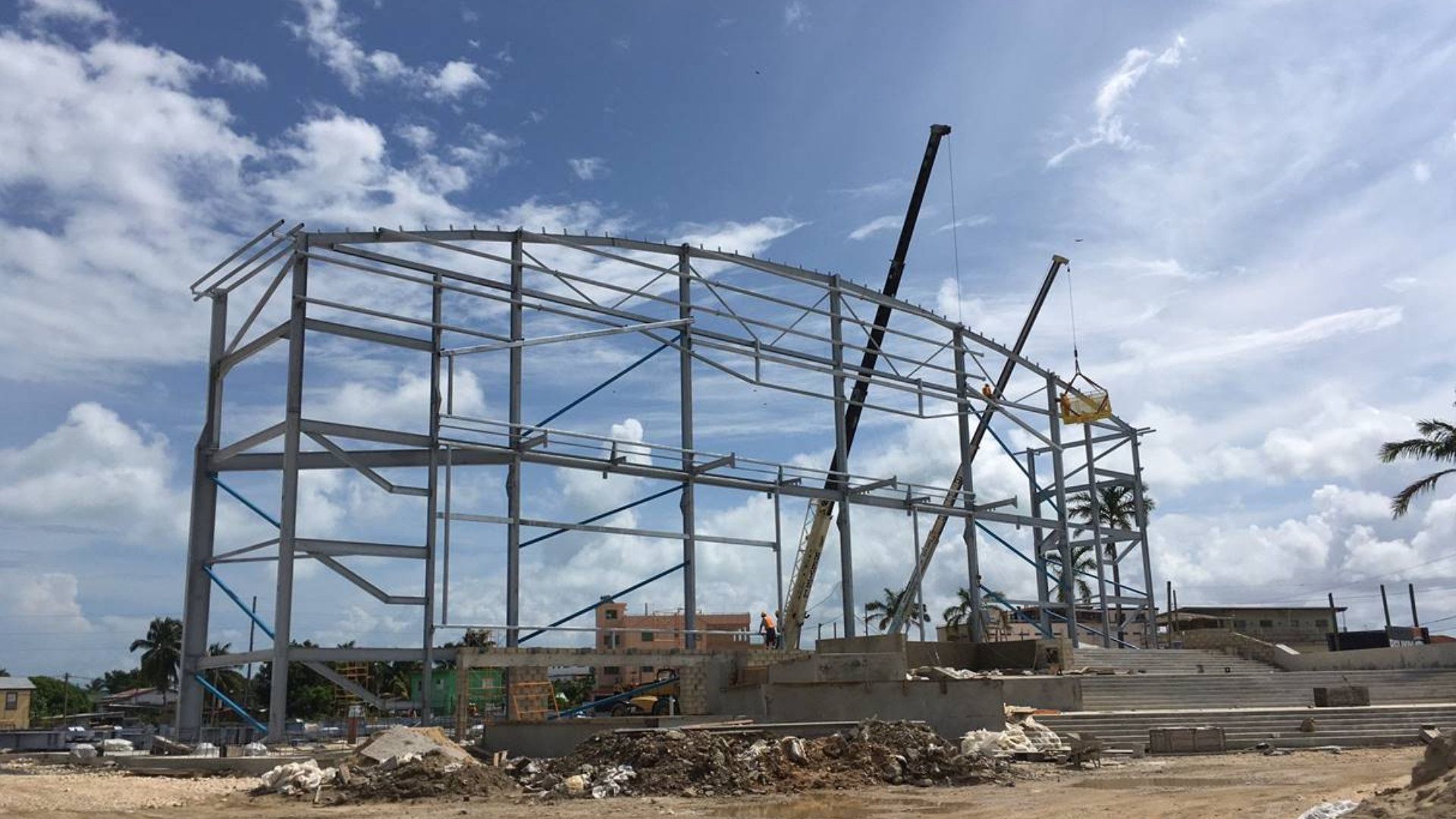 A large metal structure is being built in a dirt field.