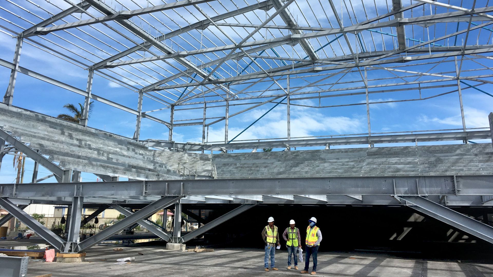 Three construction workers are standing in front of a building under construction.