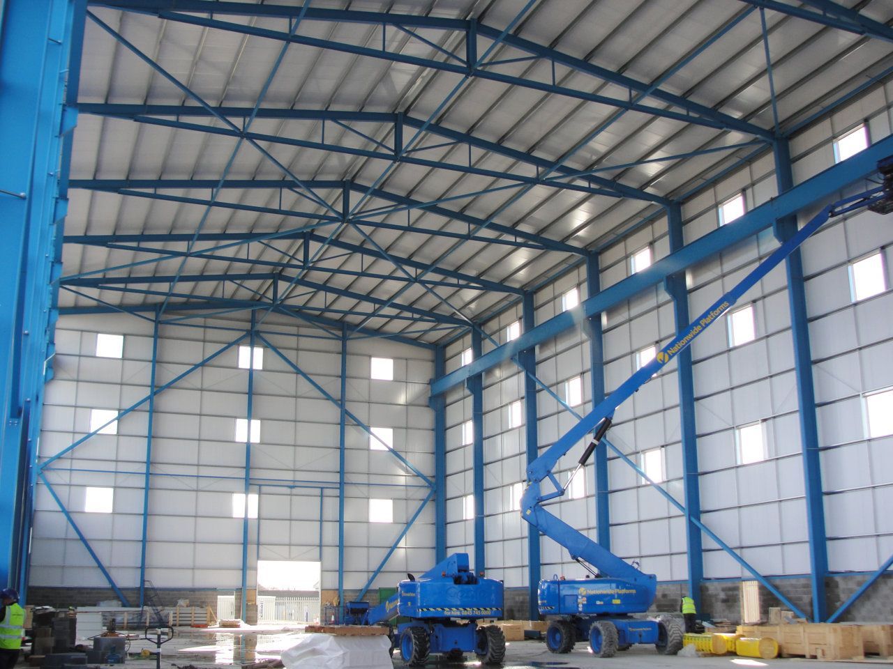 A blue crane is inside of a large building