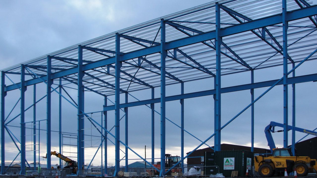 A large metal structure is being built with a blue sky in the background