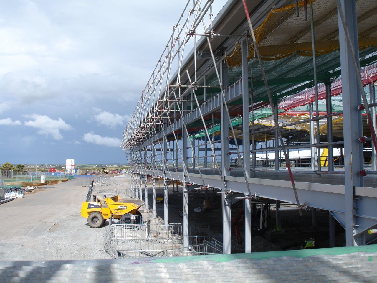 A yellow bulldozer is parked in front of a building under construction