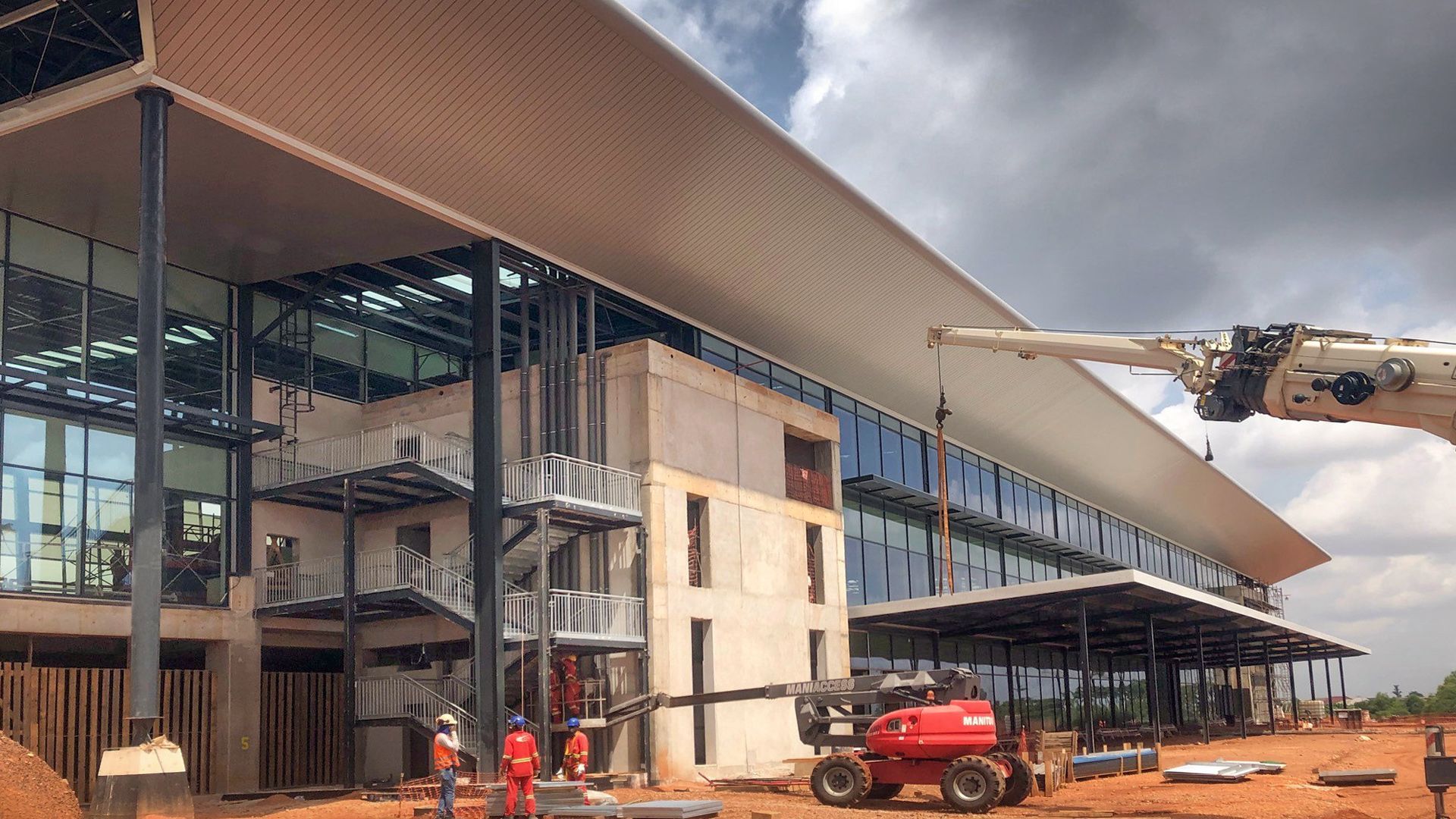 A large building is being built in the middle of a dirt field.