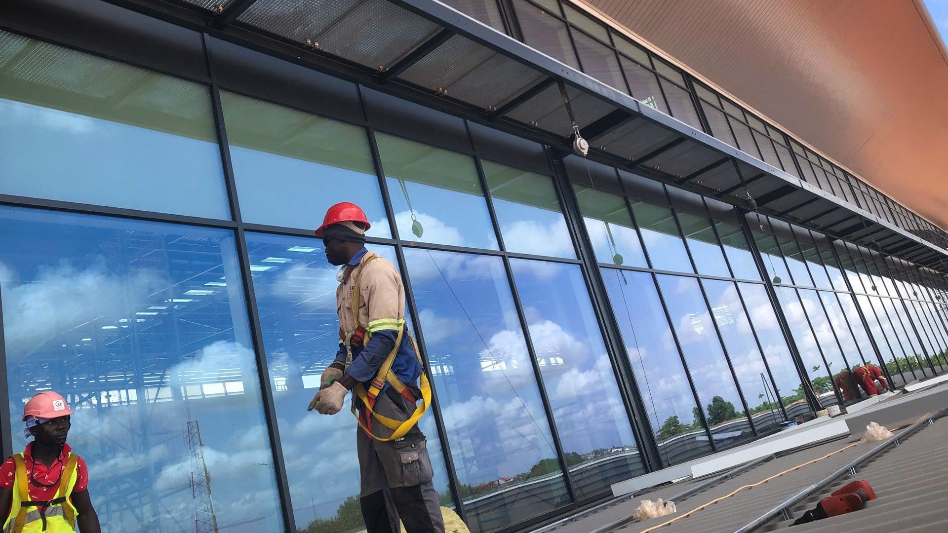 A man wearing a hard hat is standing in front of a building.