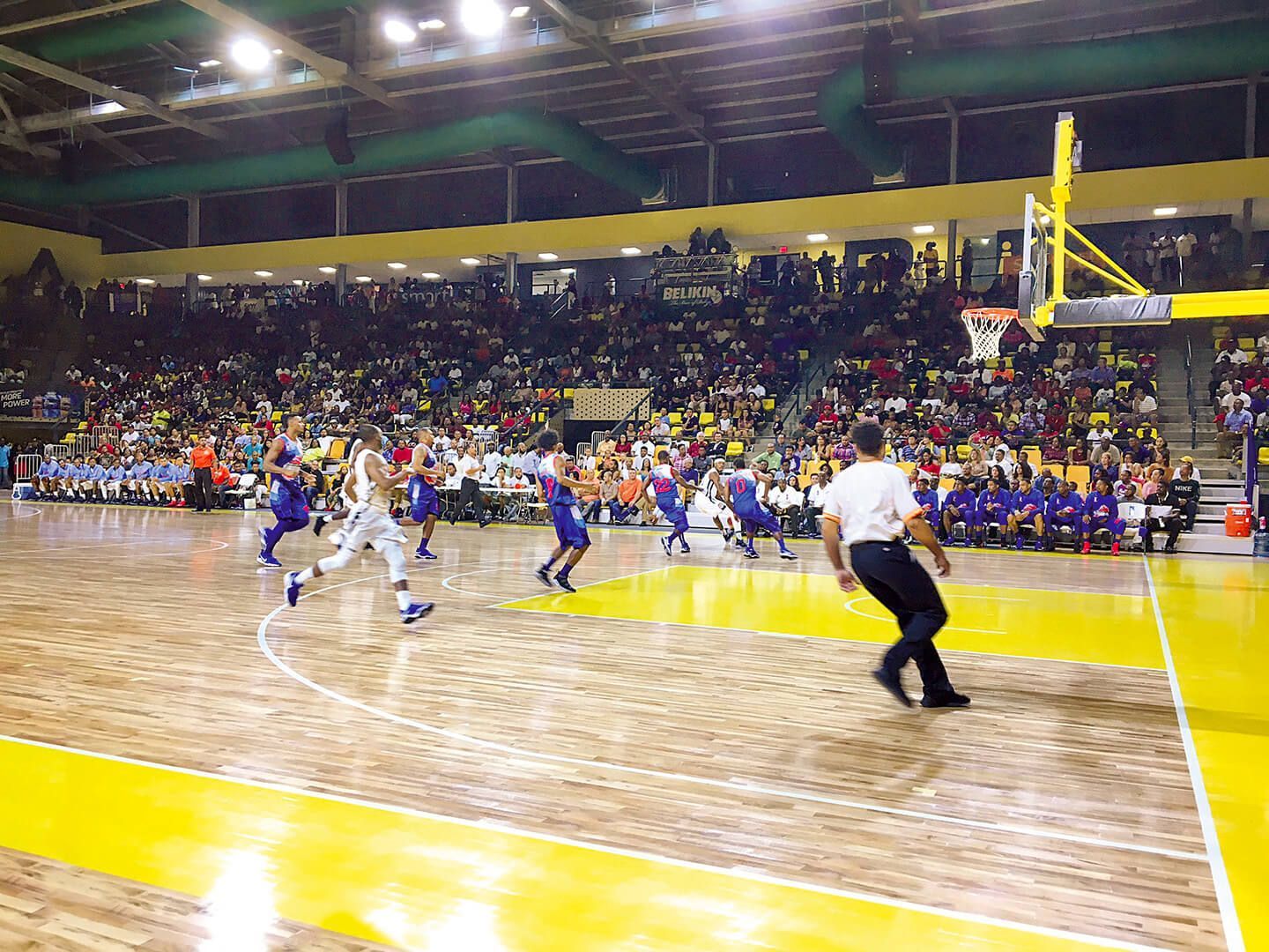 A group of people are playing basketball on a court in front of a crowd.