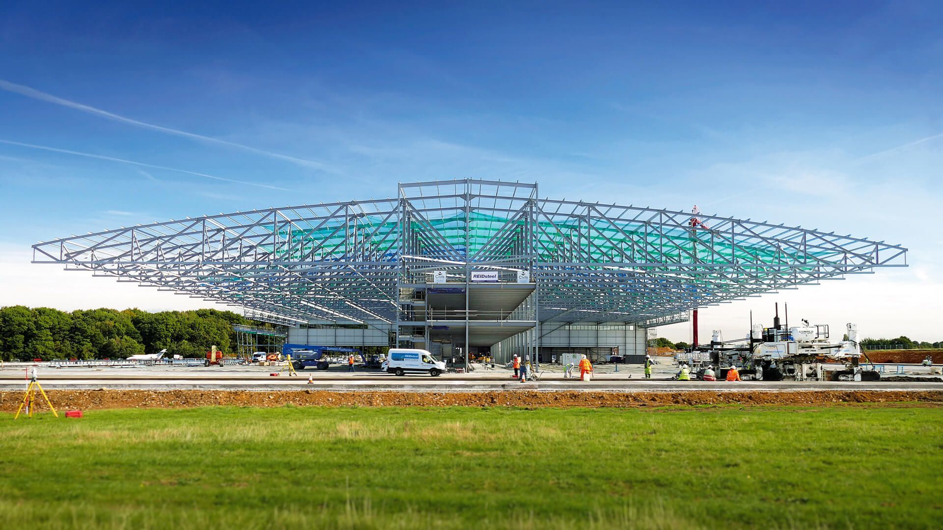 A large building is being built in the middle of a grassy field.